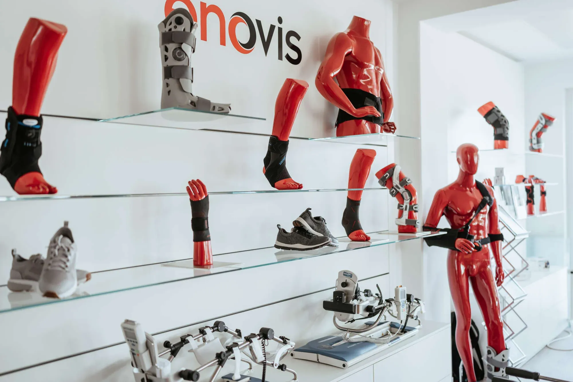 Display of prosthetic limbs and orthotic devices on glass shelves at Anovis showroom, featuring red and black prosthetic legs, arms, hands, and full-body mannequins demonstrating advanced prosthetic technology